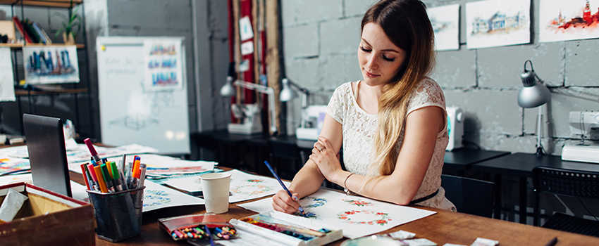 Woman working on art at her desk