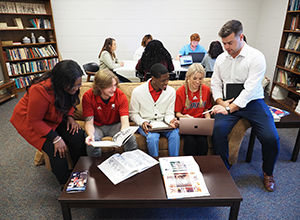 Group of communication students working together on couch in library.