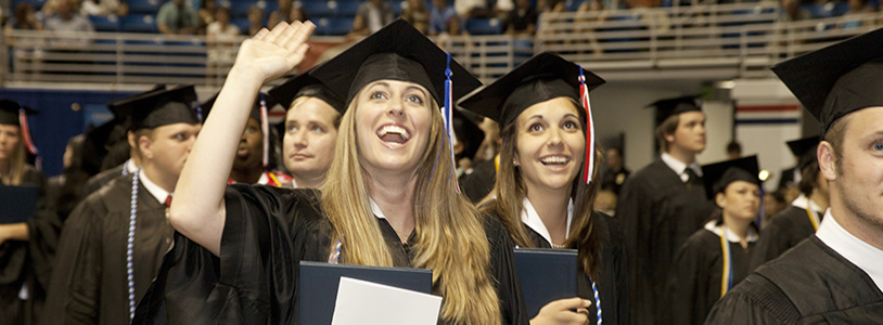 Student smiling and saving in cap and gown