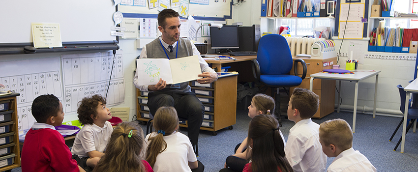 Male teacher reading book to class.