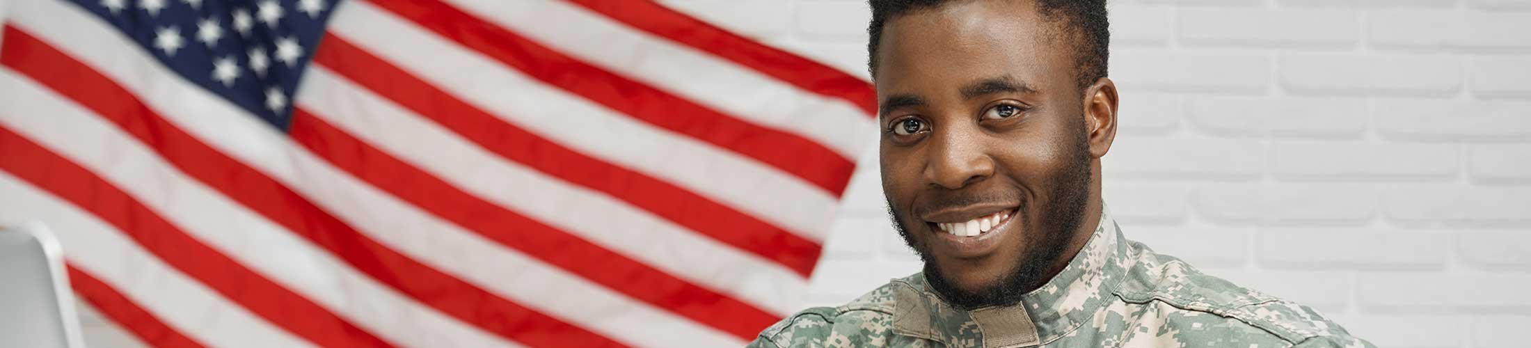 Veteran male standing next to American flag.