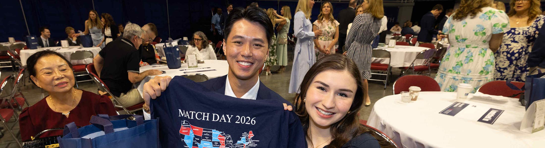 Student holding up Match Day shirt with his family.