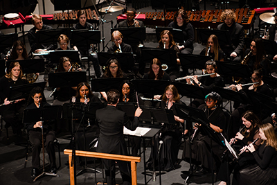 Students playing instruments with conductor.