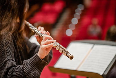 Student playing a flute looking at music sheet.