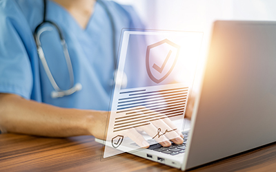 Medical worker typing on laptop.