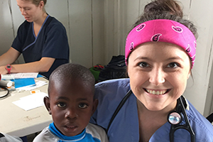 Student in scrubs holding chlld.