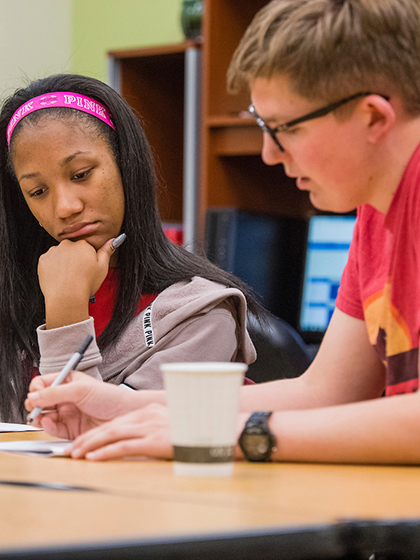 Advisor helping student while they are looking at paper.