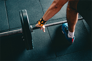 Person picking up barbell with weights on it.