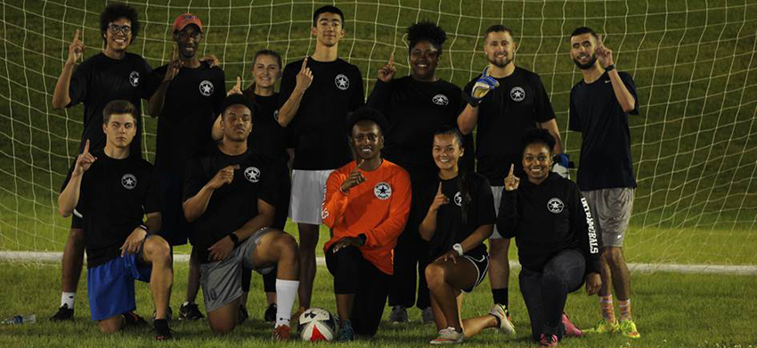 Students in front of the soccer goal holding up number 1 with hands