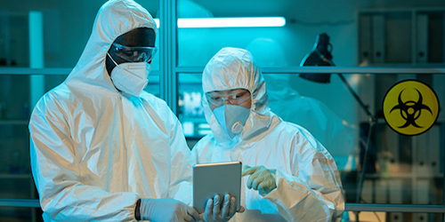 Two people working in a lab with safety suits on.