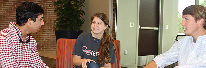 Three students sitting and talking inside of Mitchell College of Business.