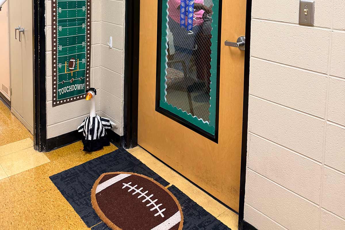 Goose dressed in referee uniform with football mat outside of an office.