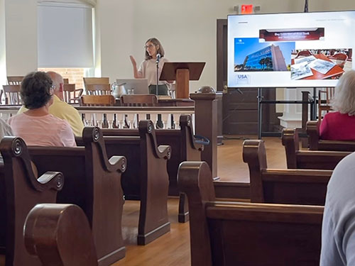 Deborah Gurt speaking to an audience in the Monroe County Museum.