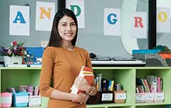 Teacher holding books in classroom.