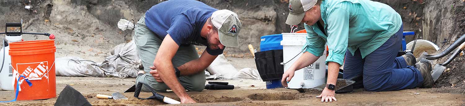 Emily Warner, right, with the USA Center for Archaeological Studies, and Thomas Grace, with Wiregrass Archaeological Consulting, bisect a feature in the soil at a site that is along the route for a proposed Mobile Bay bridge.